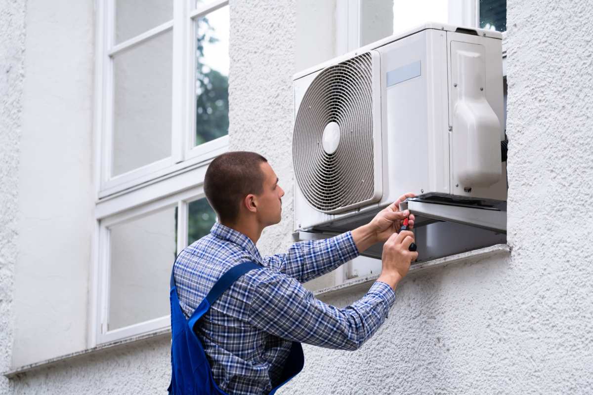 A technician installing a window AC unit